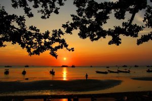 The Koh Tao sunset over the beach with fishing boats lining the shore