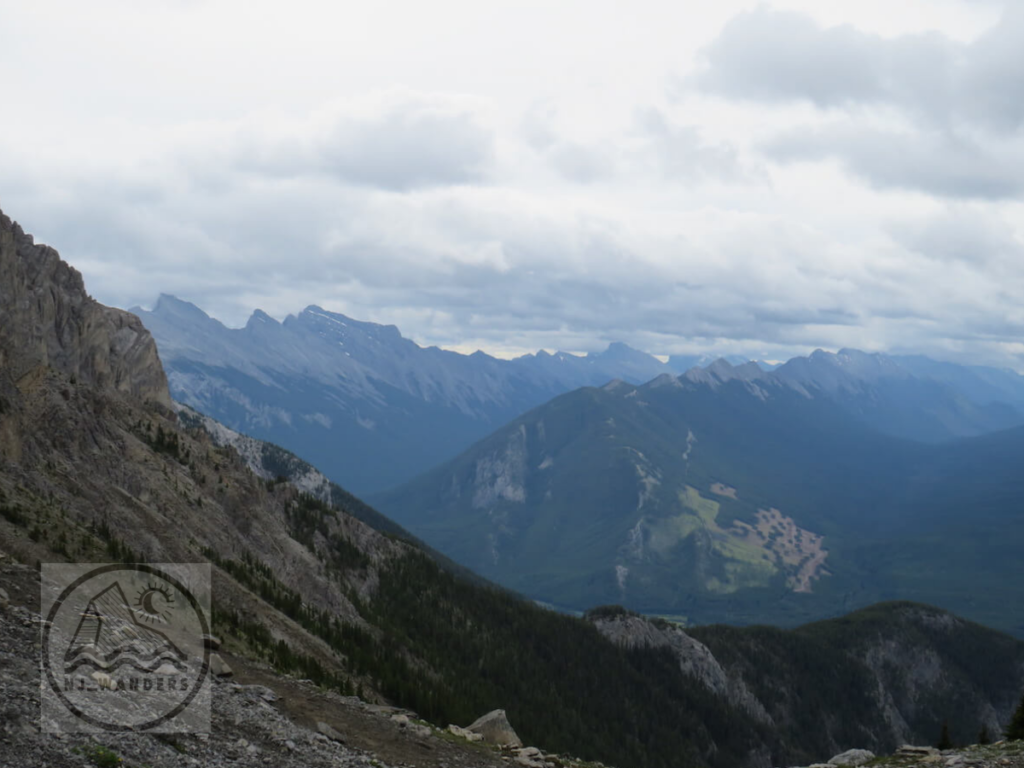 A distance shot featuring three rocky mountains with a cloudy sky