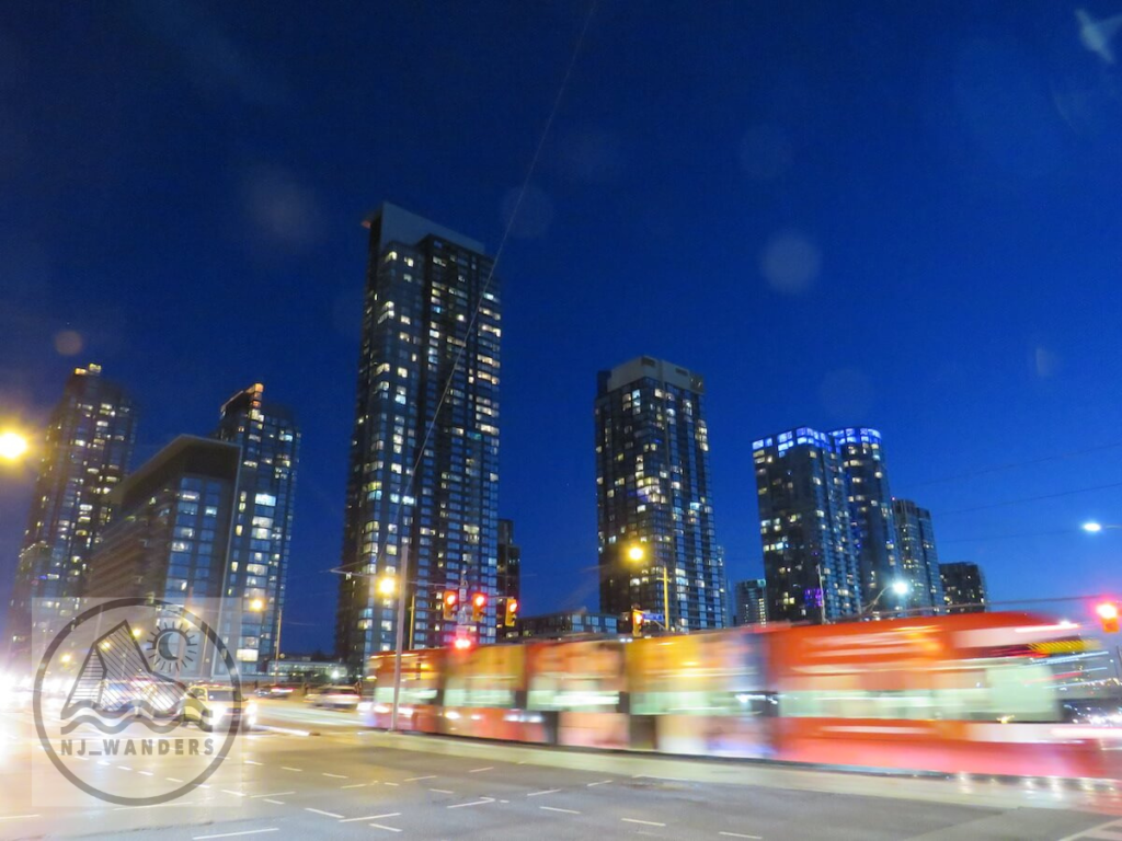 A night sky falling over 4 skyscrapers in toronto as a streetcar passes