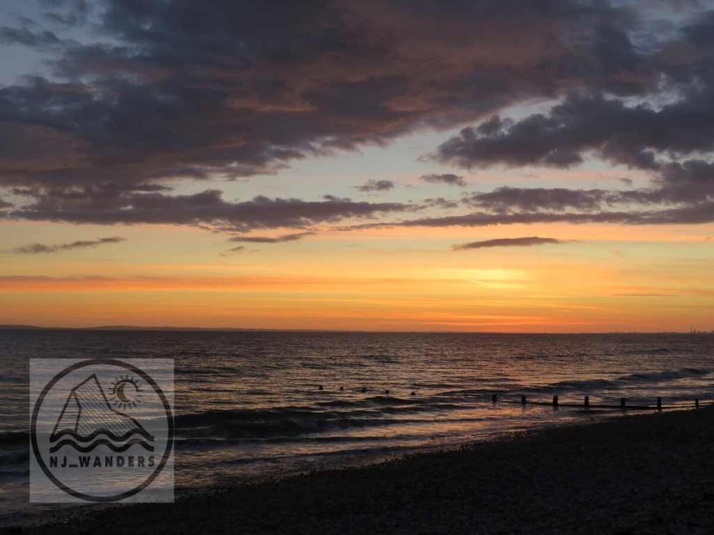 A bright orange and yellow moody sky sunset over the sea at low tide