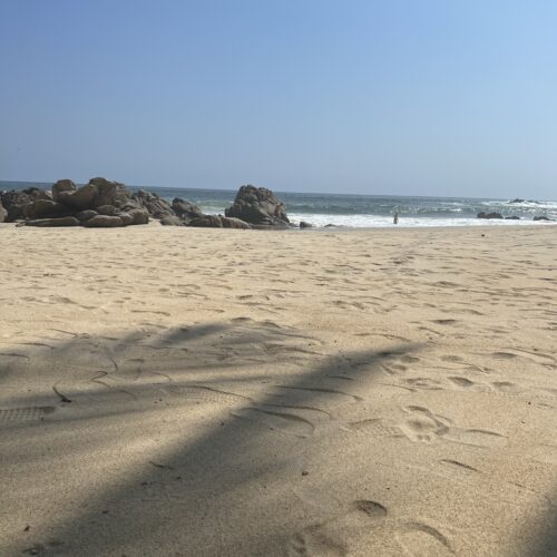 a sandy beach with rocks as the sand meets the sea