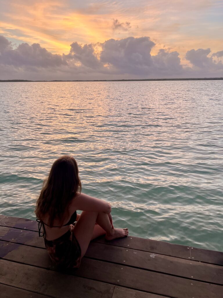 Me sitting on a dock at Lake Bacalar enjoying the sunrise