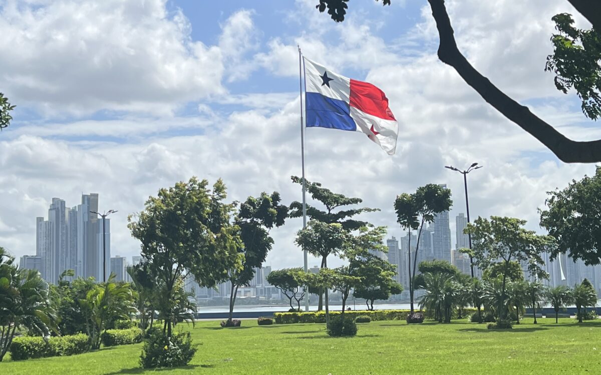 The panama flag flying in the wind with skyscrapers lining the backdrop