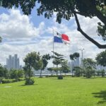 The panama flag flying in the wind with skyscrapers lining the backdrop